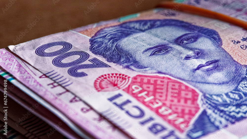 Obraz premium An organized stack of Ukrainian hryvnia banknotes, carefully fastened with a rubber band, exemplifies a bundled collection of Ukrainian currency, including 200-hryvnia notes.