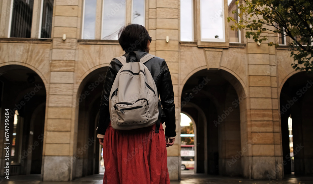 Fototapeta premium Attractive Woman Walks In City With Backpack, Looking Around