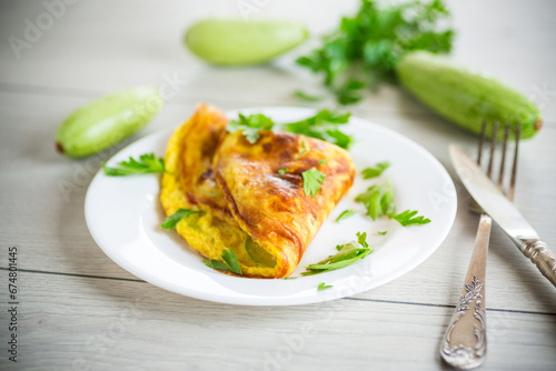 Fried omelet with zucchini, on a wooden table.
