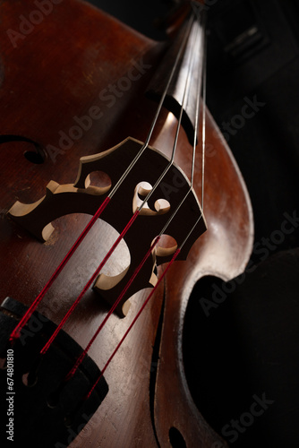 Wooden musical string instrument. Close up. Double bass bridge and strings. Contrabass in a dark. Shallow depth of field photo