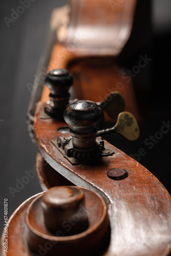 Ancient brown double bass neck, double bass scroll and tuning pegs. Vintage Doble bass head with stock with strings and tuners, music concept. Close up. Shallow depth of field