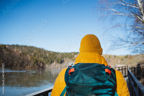Back view of man with backpack on hike, guy tourist enjoying outdoor recreation in winter, concept of hiking route in park.