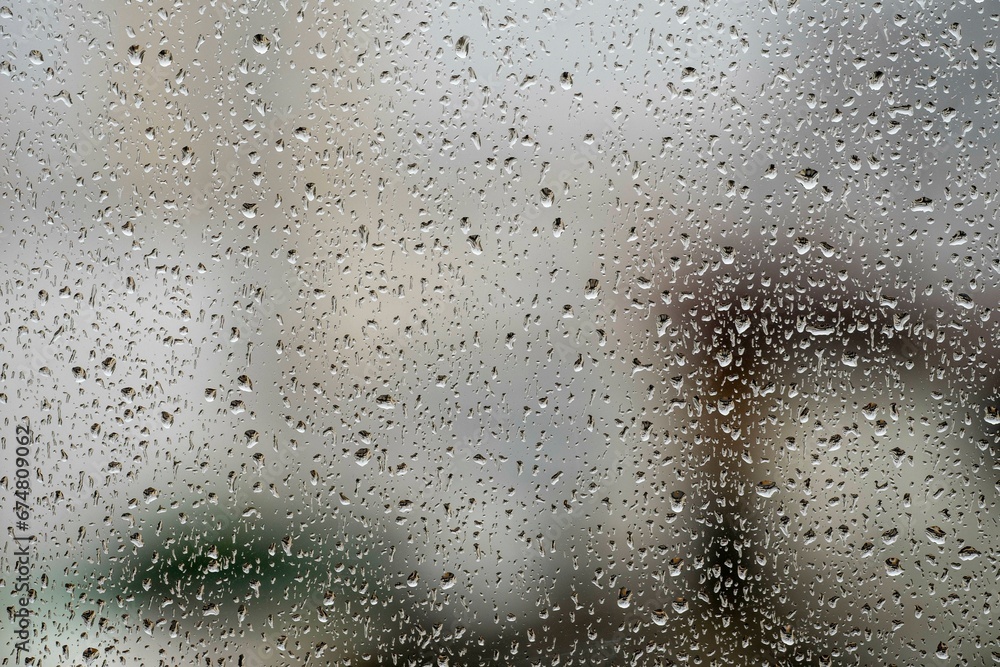 window glass with raindrops showing blurred city in the background