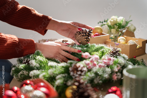 Woman decorating beautiful Christmas wreath.