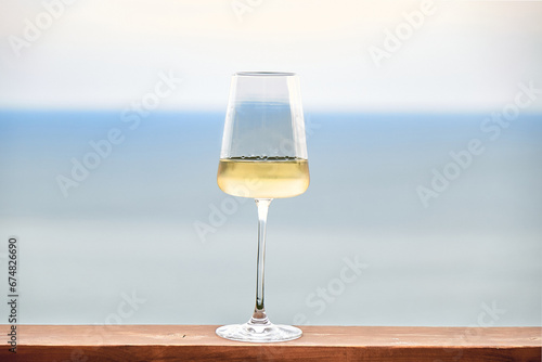 White wine in glass against a background of blue sky and sea. Front view. Copy Space.