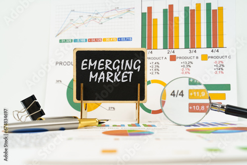 Against the background of business graphs, a board with the inscription - emerging market photo