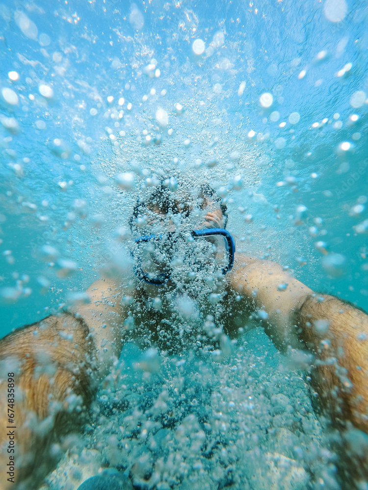 Swimmer in a mask swims in bubbles underwater