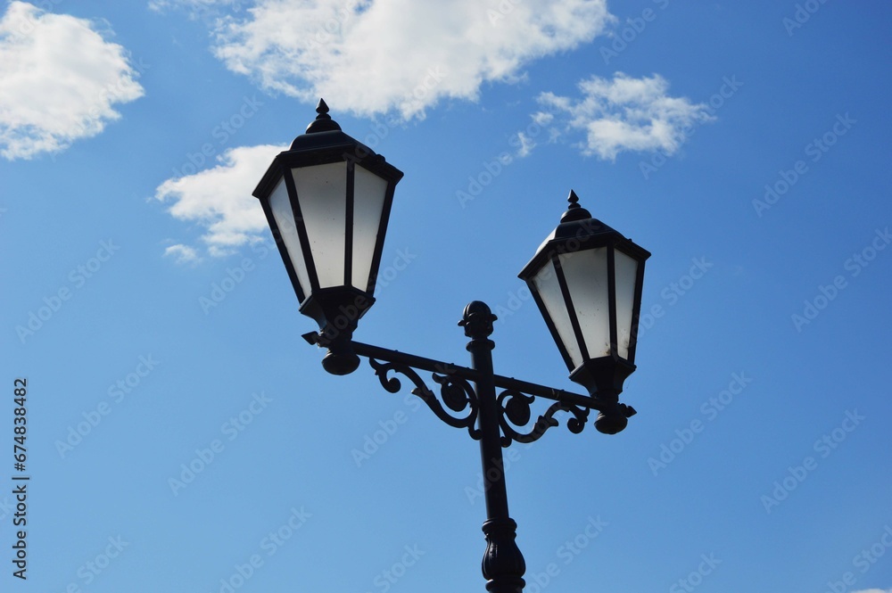 Black street glass lanterns against a blue sky. City lighting.