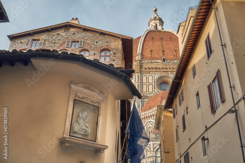 Fototapeta Naklejka Na Ścianę i Meble -  Brunelleschi's dome of the cathedral of Santa Maria del Fiore in Florence seen from a small street, on the left a shrine of the Virgin Mary