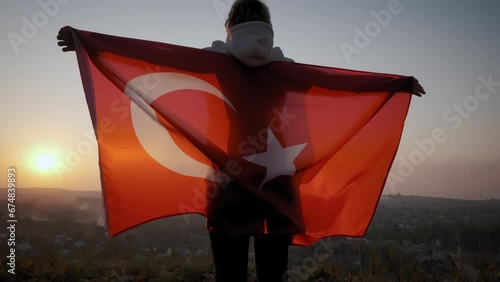 Back view of happy woman with turkish national flag standing outdoors at sunset. Wide footage photo