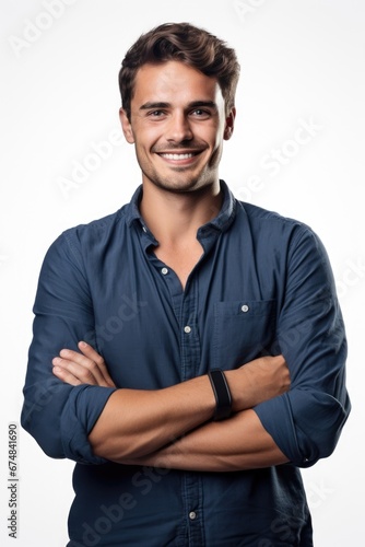 A man wearing a blue shirt smiles confidently as he stands with his arms crossed. This picture can be used to convey positivity, confidence, or professionalism