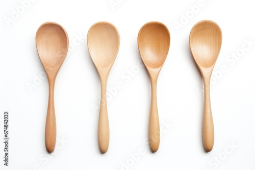 Four wooden spoons neatly lined up on a white surface. This versatile image can be used to showcase kitchen utensils, cooking or baking recipes, or even in articles about the art of cooking. photo