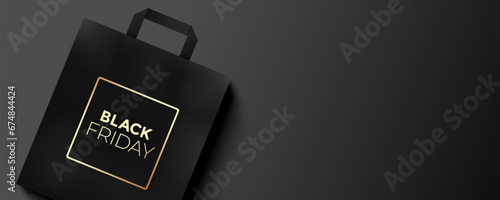 Black Friday elegant banner design with golden printed shopping paper gift bag lying on a dark background.