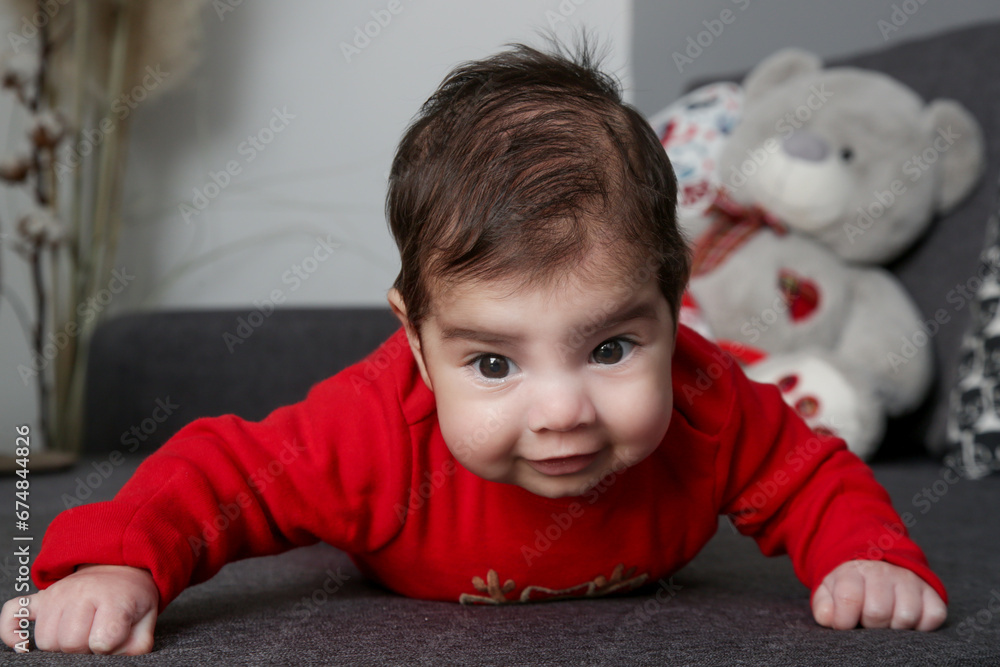 Portrait of adorable newborn baby in red bodysuit on the sofa Portrait of adorable newborn baby in red bodysuit on the sofa