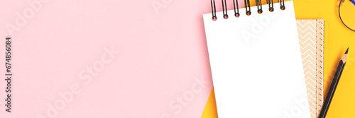 Banner with clean notepad mockup, eyeglasses and stationery on a pink and yellow background.