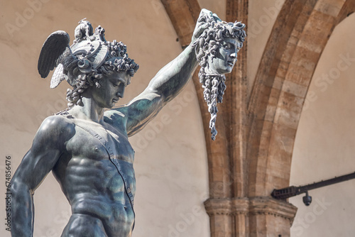 Bronze statue of Perseus with the head of Medusa, masterpiece by Benvenuto Cellini in Florence, Loggia dei Lanzi in the background in Florence photo
