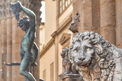 Close-up of the lion statue in Piazza della Signoria in the Loggia dei Lanzi, in the background bronze statue of Perseus by Benvenuto Cellini in Florence
