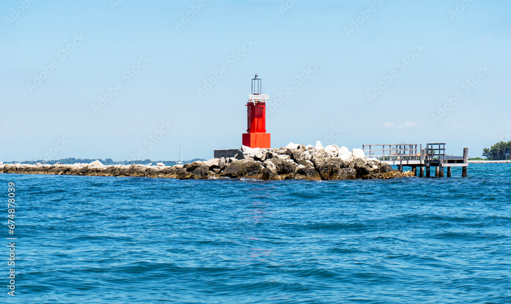 Red lighthouse in the sea, sunny day. Ligniano, St.Andrea island, Friuli, Italy