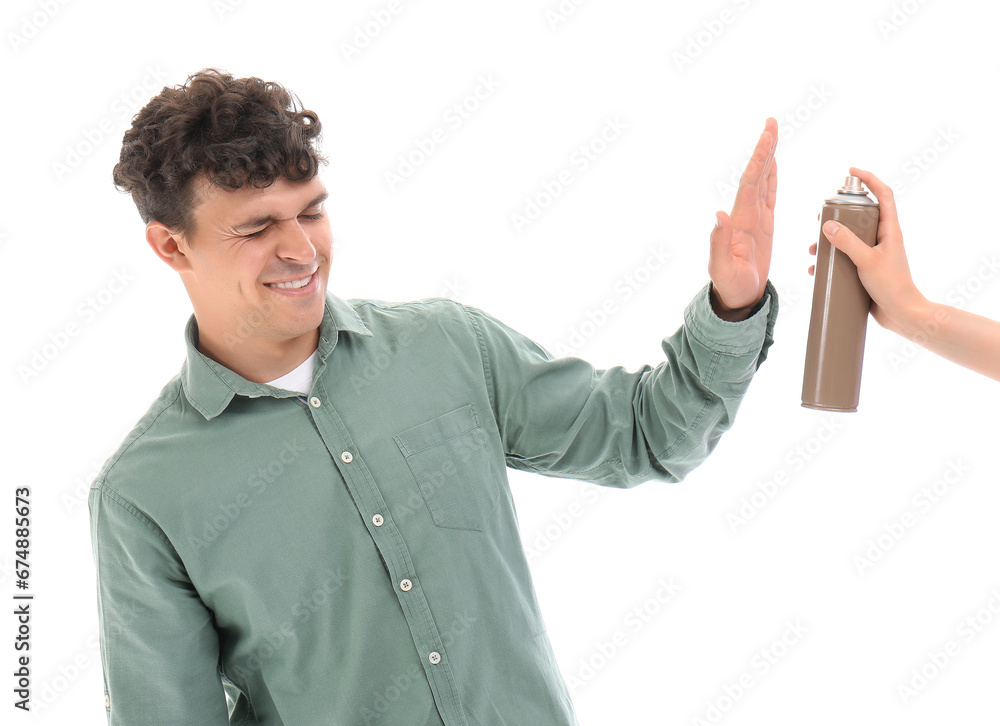 Displeased young man refusing to apply hair spray on white background Displeased young man refusing to apply hair spray on white background