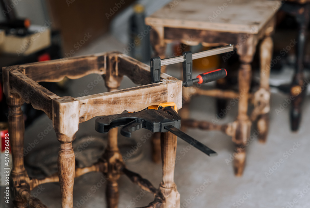 Clamp, a special tool for gluing and fixing a wooden chair in the workshop. Photography, furniture concept, craft. Clamp, a special tool for gluing and fixing a wooden chair in the workshop. Photography, furniture concept, craft.