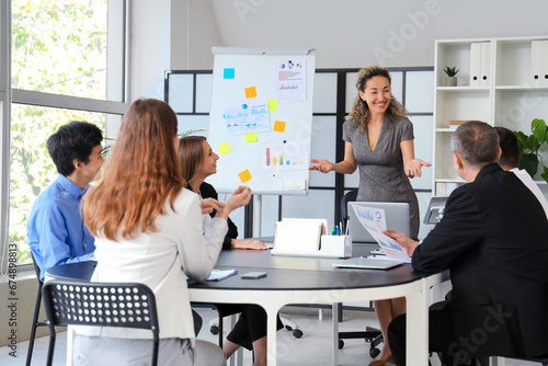 Happy businesswoman giving presentation to colleagues at meeting in office photo