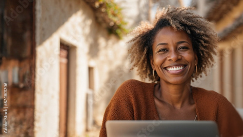 Beautiful African American mature businesswoman working on laptop, freelance woman with computer on table in comfortable space, concept of nomadic life and remote work, space for text photo