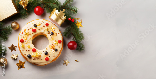 Flat lay with Roscon de Reyes decorated with berries and candies, tiny crown and Christmas tree branch on white background. Typically enjoyed Three Kings Day, Epiphany day