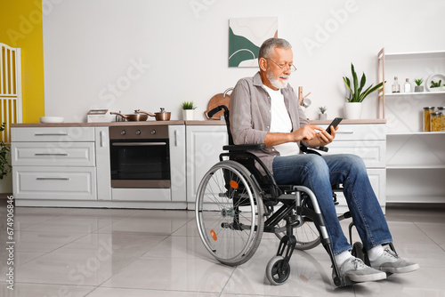 Senior man in wheelchair using mobile phone at home photo