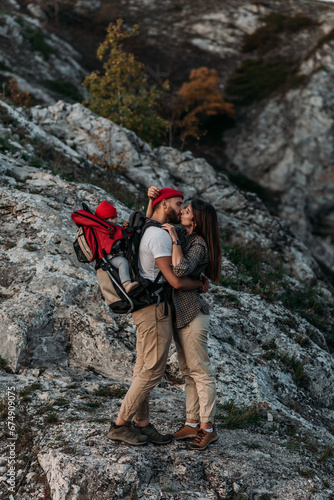 Traveling with children. A couple in love with a child in the mountains. A traveling couple in hiking gear in the mountains. A traveling family. Travelers on the background of mountains. Happy family