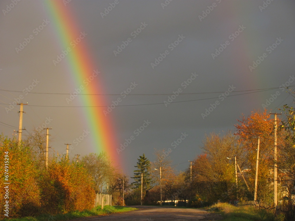 Morning rainbow in the village in autumn