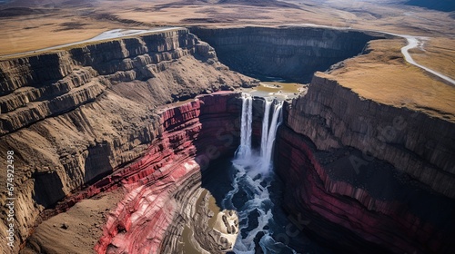 Aerial view on Hengifoss waterfall with red stripes sediments and old soil volcanic formation in Iceland. Beautiful Icelandic nature during stormy day.