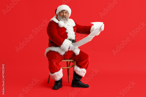 Santa Claus reading letter on red background