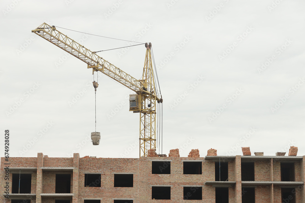 View of a large construction site with buildings under construction and multi-storey residential homes. Tower cranes in action on blue sky background. Housing renovation concept. Crane during