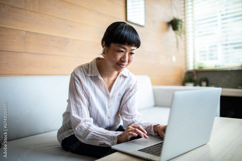 Smiling young woman using laptop sitting on couch at home Smiling young woman using laptop sitting on couch at home