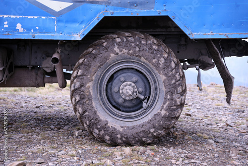 Wheel closeup in a countryside landscape with a mud road. Off-road 4x4 suv automobile with ditry body after drive in muddy road area