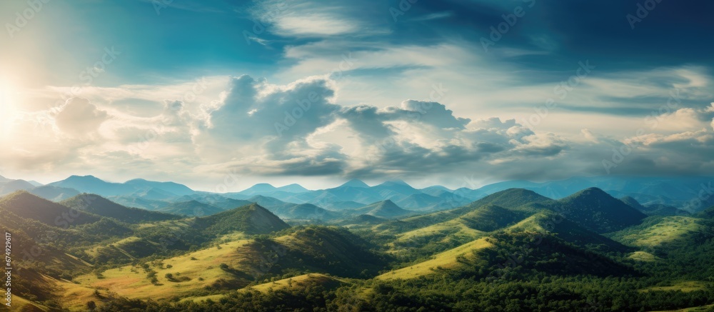 The beauty of the green mountains illuminated by the golden light of the setting sun against a backdrop of a clear blue sky with fluffy white clouds showcases the breathtaking nature and lan The beauty of the green mountains illuminated by the golden light of the setting sun against a backdrop of a clear blue sky with fluffy white clouds showcases the breathtaking nature and lan