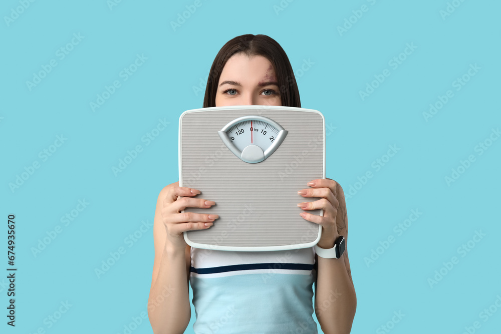 Beautiful young sporty woman with scales on blue background. Weight loss concept Beautiful young sporty woman with scales on blue background. Weight loss concept