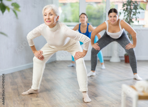 Sporty motivated young elderly women warming up with energetic dances before strength training in gym studio