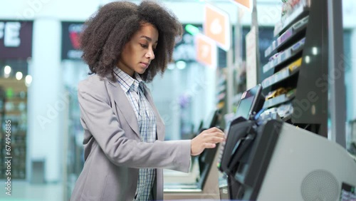 Female shopper using a self-service cashier checkout in a supermarket. Customer scanning produce items using at grocery store self serve cash register. cashier terminal woman pay for products online photo