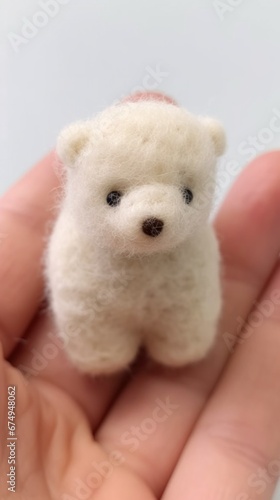 A hand holding a small white bear