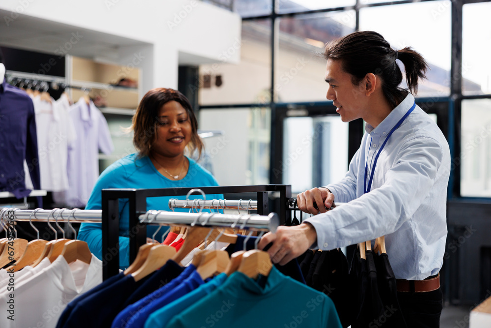 Obraz premium African american customer looking at casual wear, shopping for stylish merchandise in modern boutique. Shopaholic woman wanting new wardrobe, buying fashionable clothes in clothing store