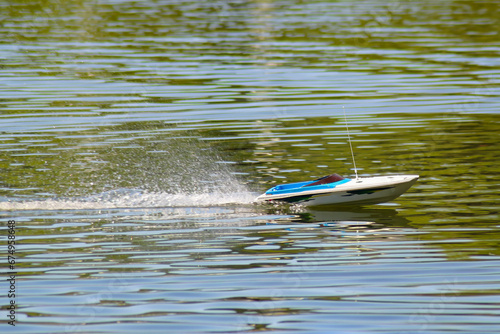 A model of a boat in motion on the water of a calm lake on a sunny summer day. Trace and splashes on the water from the movement of the boat