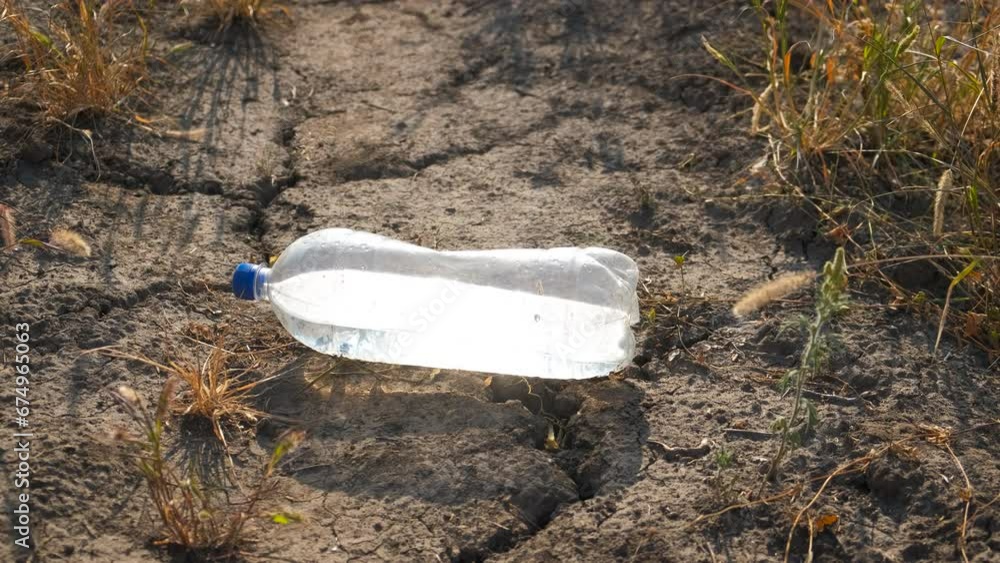Land suffering from drought in sun. A part of urban land affacted by hot weather with a bottle of watter under sun.