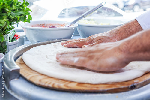 Man chef hand making craft pizza top view spreading pizza dough