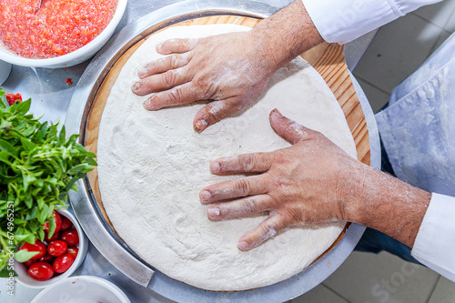 Man chef hand making craft pizza top view spreading pizza dough