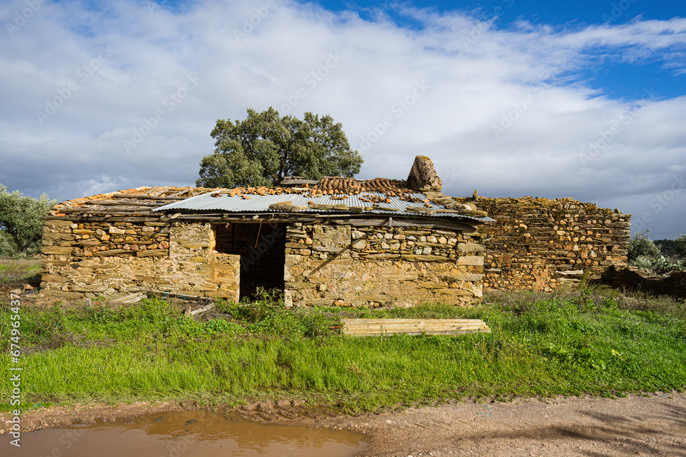 ruins of a brick house with part of the roof intact with an image of a decrepit environment, Malpica do Tejo, Castelo Branco district. November 2023