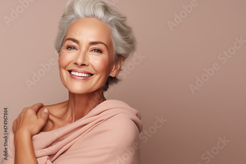 slim pensioner woman positive cosmetology hugs her shoulders smooth skin care self confidence isolated beige color background photo