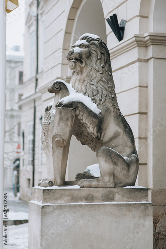 A stone sculpture of a lion, covered with snow, sits at the entrance to the Lviv Town Hall. Ukrainian winter.