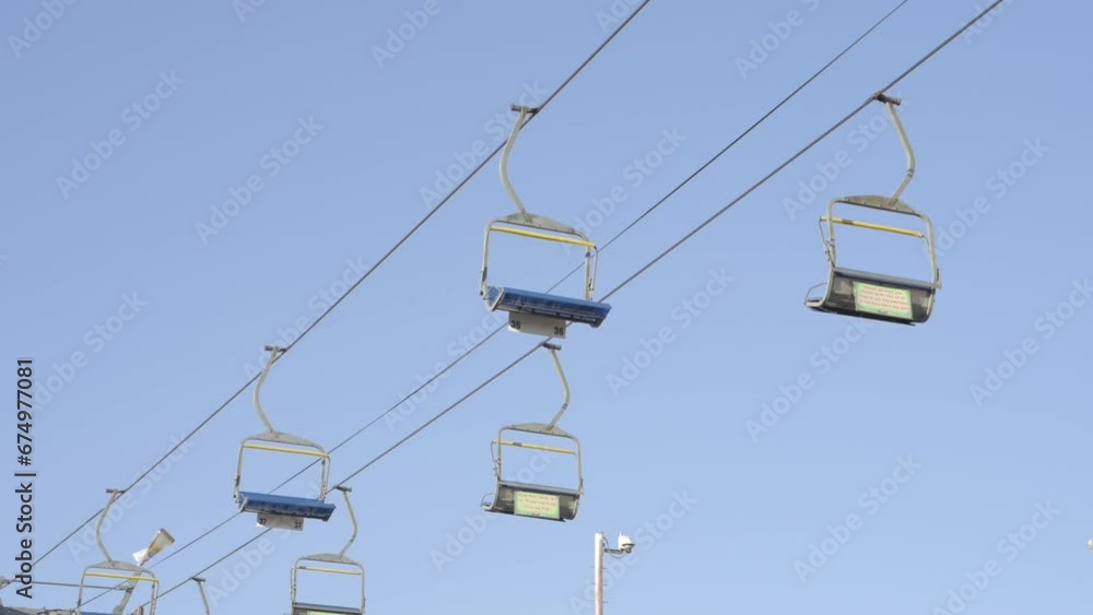 This video shows a gondola chair lift with a blue sky background. This video shows a gondola chair lift with a blue sky background.