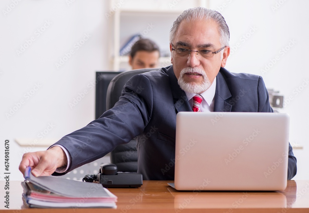 Old boss and young male employee in the office Old boss and young male employee in the office